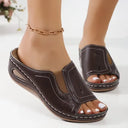 Brown leather-look open toe wedge mule sandals with white contrast stitching, angled front view on feet.