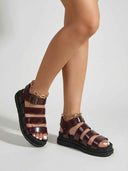 Wine red flatform gladiator sandals with black lug sole, worn with anklets, showing gold chain ankle detail, angled three-quarter view.