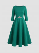 Daisy green A-line midi wedding guest dress with boat neckline, three-quarter sleeves and rhinestone belt, front view.
