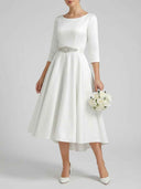 Daisy white A-line midi dress with bateau neckline, three-quarter sleeves and rhinestone embellished waist belt, straight-on front view.