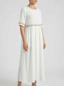 White embroidered short sleeve maxi dress with floral trim at waist and sleeve hems, angled side-front view.