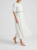 White short sleeve maxi dress with floral embroidery trim at waist and cuffs, angled side view.