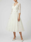Daisy ivory floral appliqué V-neck midi dress with three-quarter sheer sleeves, full A-line tulle skirt, and satin bow belt, three-quarter front view.