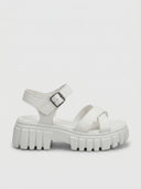 White chunky platform sandals with lug sole and adjustable hook-and-loop ankle strap, angled side view.