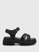 Black chunky platform sandals with lug sole, crossover toe straps and hook-and-loop ankle strap, side view on white background.