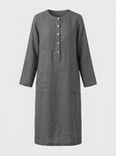 Daisy relaxed shift dress in dark grey woven, partial button placket, three-quarter sleeves and two front patch pockets, front view.