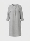 Daisy relaxed shift dress in light grey woven, partial button placket, three-quarter roll-tab sleeves and two front patch pockets, front view.