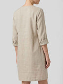 Daisy relaxed shift dress in oat woven, roll-tab three-quarter sleeves and straight knee-length silhouette, back view on light grey background.