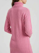 Pink ribbed knit turtleneck mini dress showing ribbed hem and cuff detail, angled back view.