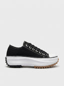 Black platform trainers with white laces, chunky white midsole and black ripple-cut rubber outsole, side view.
