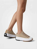 Angled side view of tan suede-look platform trainers showing chunky white midsole and black ripple-cut outsole.