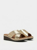 Gold metallic wedge mule sandals with wide overlapping cross straps and espadrille rope-trim heel, angled three-quarter view.