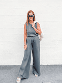 Woman in a charcoal gray sleeveless belted blazer jumpsuit with wide legs, front view.