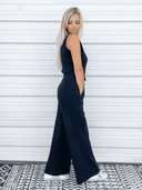 Navy sleeveless belted jumpsuit with wide legs, side view on white background.