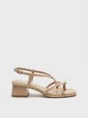 Apricot strappy flat sandals with crossover toe straps and gold orb accent, side view on white background.