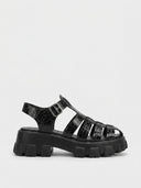 Black crocodile-embossed cage flatform platform sandal with buckle ankle strap and lug sole, angled view on white background.
