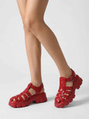 Red crocodile-embossed cage flatform sandals worn on feet, angled view showing lug sole platform.