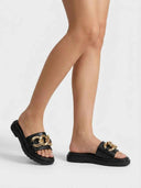 Black chunky gold-chain platform slide sandals worn on a model, angled view showing flatform sole height.