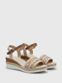 Pair of natural beige espadrille wedge sandals with jute-braided wedge sole and tan buckle ankle straps, angled view.
