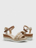 Pair of beige espadrille wedge sandals showing geometric embroidered beaded forefoot strap detail and jute rope wedge trim, angled view.