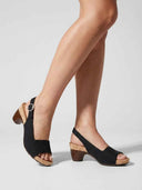 Black cork platform block heel slingback sandals on model's feet, angled view showing wooden heel and cork footbed.