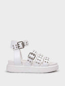 White chunky flatform sandals with three buckle straps and silver eyelet detail across forefoot, wide ankle strap, side view on white background.