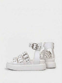 White flatform sandals with eyelet hardware detail and buckle ankle strap, angled view on plain white background.