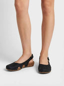 Black closed-toe slingback sandals with cork footbed, worn on feet, front view showing scalloped cutout detailing.