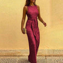 Red sequin jumpsuit with tie waist, worn by a model, angled view on a yellow background.