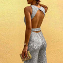 Silver sequin jumpsuit with open back and waist detail, angled back view.