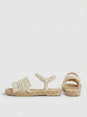 Cream flat espadrille slide sandals showing fringed toe strap and braided jute sole from side and rear angle.