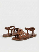 Pair of brown flat sandals with smooth crisscross straps and ruched ankle band, angled overhead view.