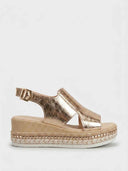 Rose gold metallic espadrille wedge platform sandals with wide cross-strap forefoot and slingback buckle, side view on white background.