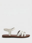 White flat sandals with crisscross front straps and elastic ruched ankle strap, side view on white background.