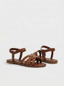 Brown flat sandals with crisscross woven straps and elastic ankle band, angled view on white background.