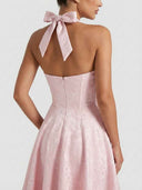 Pink jacquard halterneck mini dress with bow tie, back view on white background.