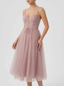 Pink spaghetti strap dress with ruched corset bodice, lace-up detail, and flared tulle skirt, front view.
