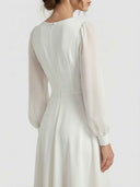 White midi dress with sheer long sleeves and back zipper, back view.