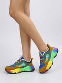 Chunky low-top trainers with rainbow gradient sole worn on feet, angled side view showing arch support profile.