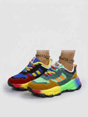Pair of chunky multicolour low-top trainers with rainbow sole, angled view on white background.