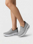 Grey slip-on platform walking trainers with air-cushion sole, worn on feet, angled three-quarter view.