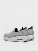 Pair of grey slip-on platform knit trainers with white air-cushion midsole, angled rear view.