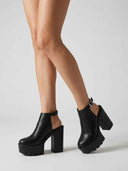Black chunky platform heels with closed toe and slingback ankle strap, worn on feet, angled view.