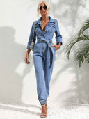 Light blue denim jumpsuit with flap pockets, front buttons, and belt, front view.