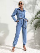 Light blue denim jumpsuit with flap pockets, front buttons, and tie waist, front view.