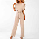 Beige jumpsuit with boat neck, short sleeves, and waist tie, front view on white background.