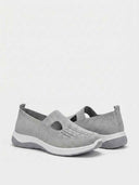Close-up of engineered-knit upper with geometric T-bar cutout and perforated mesh ventilation panels on grey cushioned trainer.