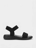 Black elastic flat sandals with plain black toe strap, ankle band, and ridged rubber sole, side view on white background.