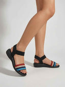 Multicolour striped elastic flat sandals worn on feet, angled view showing toe strap and ankle band.