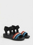 Flat sandal with red, beige, and blue striped woven elastic toe strap and black ankle band, angled view.